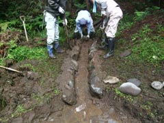 玉石を利用した池への導水路設置作業の様子の画像